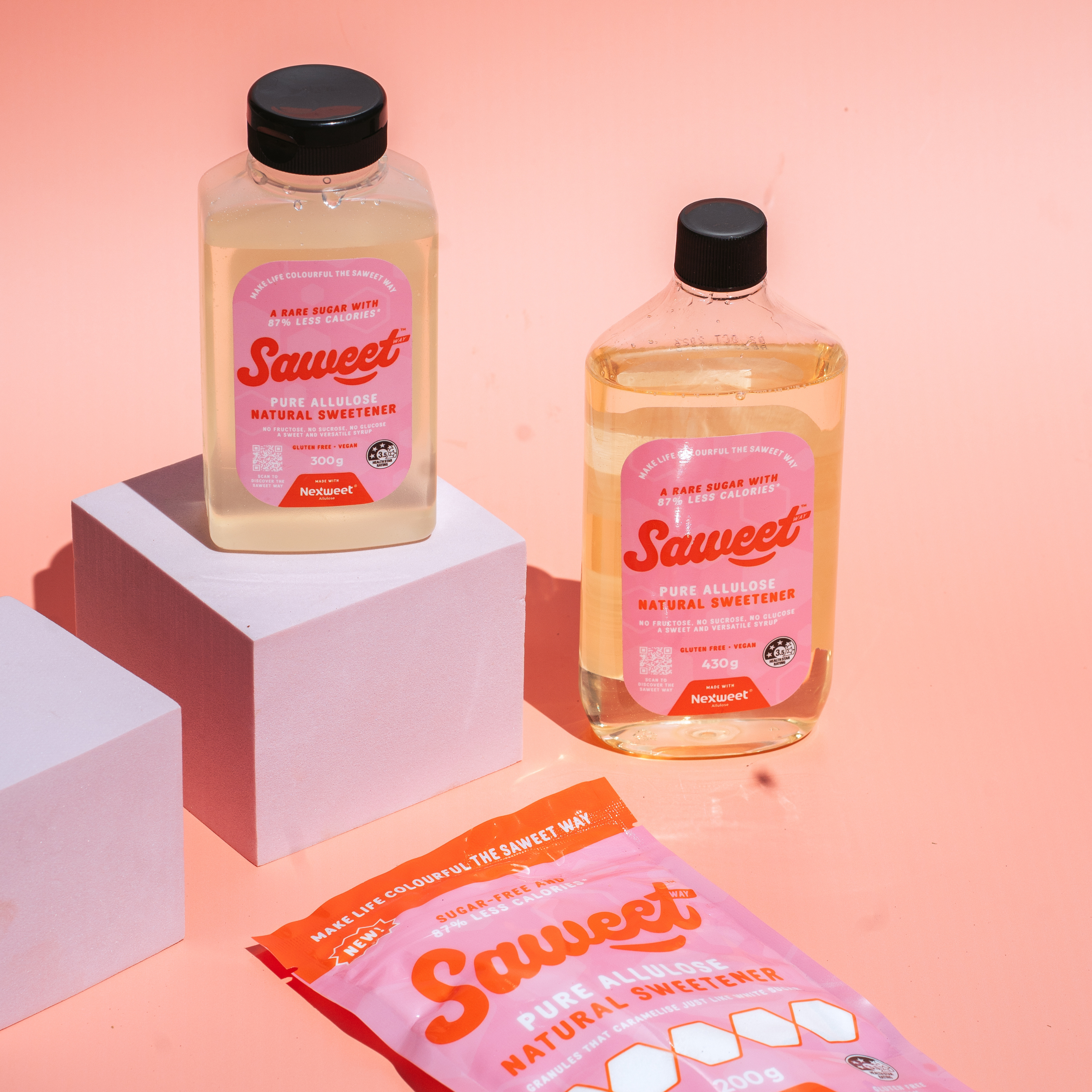 Saweet Way pure allulose natural sweetener in bottles and pouch on pink background, a low calorie sugar alternative for baking and everyday sweet swaps.